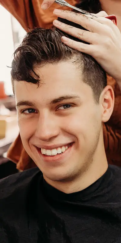 A hairstylist trims the hair of a seated client, showcasing a modern salon setting with warm lighting and focused attention on the haircut.